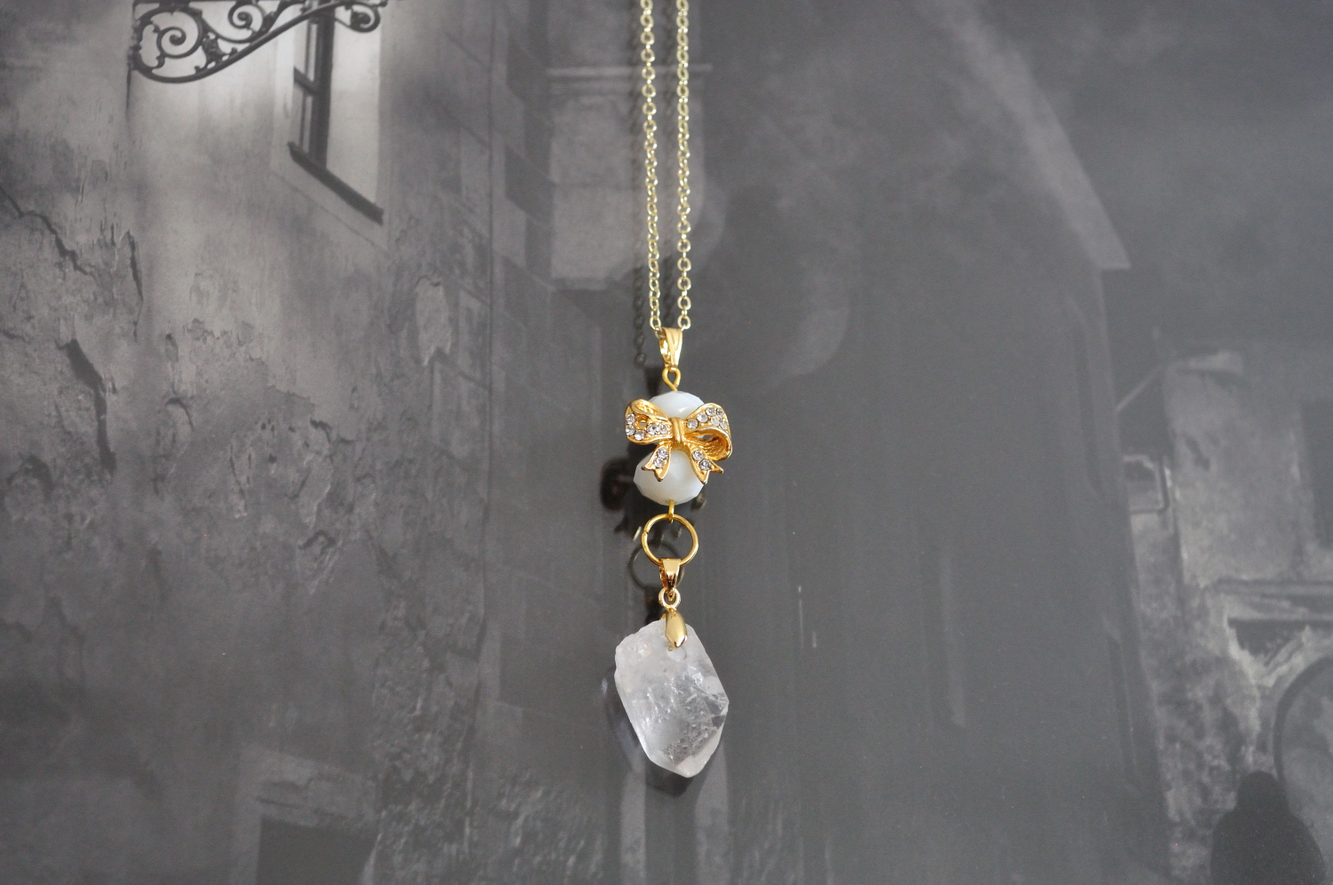 fine, gold-plated elegant necklace in gold and white with crystal gold bow and raw quartz pendant
